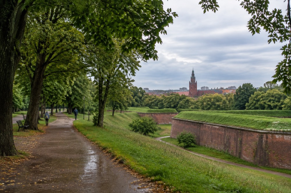A historic red brick tower rising above rooftops seen from a distance