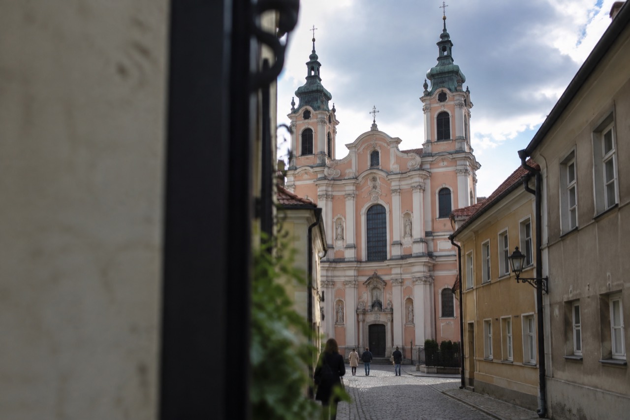 Baroque church facade with twin towers seen from a narrow street in Poznan