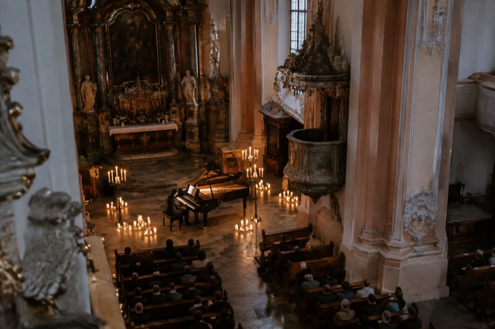 Candlelit concert setting with a grand piano in a historic interior