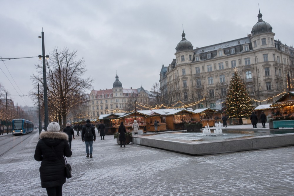 A Christmas market with wooden stall huts, string lights and a decorated square in winter