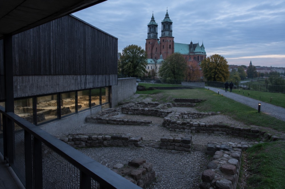 Excavated stone foundations of early medieval buildings viewed from an elevated walkway