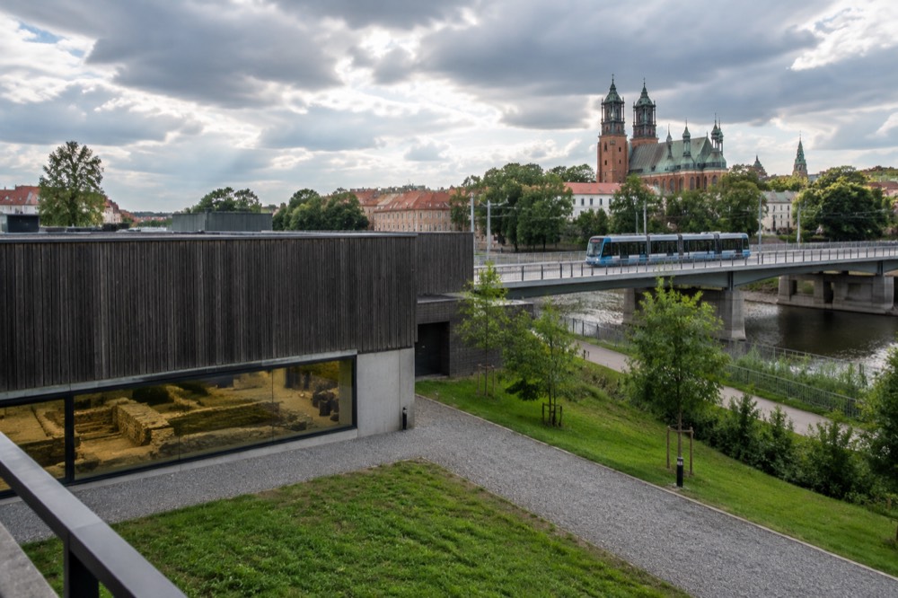 A modern tram crossing a bridge toward the cathedral island in Poznan