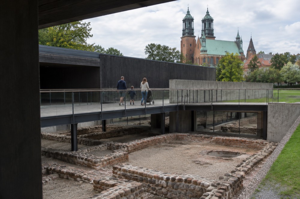 A family walking an elevated walkway over an indoor archaeological excavation