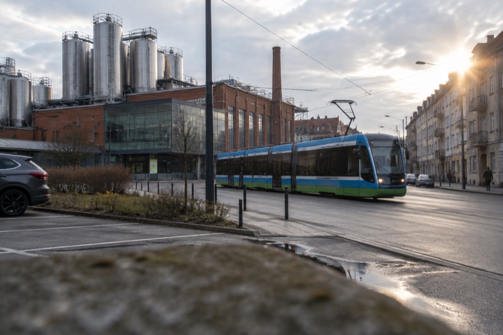 A modern Poznan tram moving along a street lined with tenement buildings
