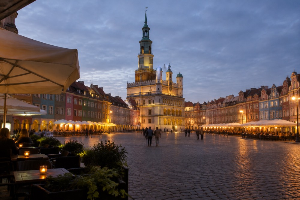 Evening view of the illuminated Old Market Square in Poznan with cafe terraces and the Town Hall tower