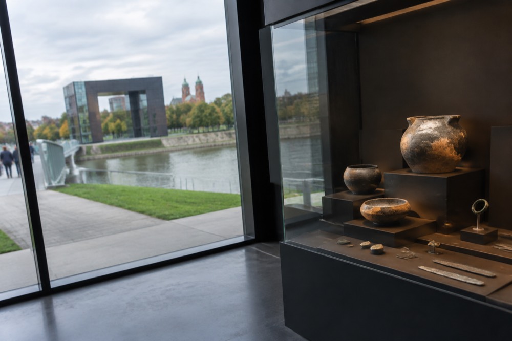 Display case with archaeological finds lit against a dark wall in a museum gallery