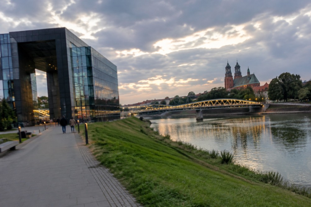 Evening view of the riverbank path and illuminated bridge leading to the cathedral island