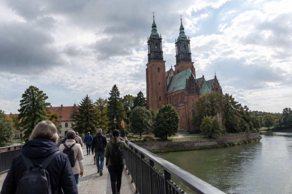 Tour group walking with a guide across a bridge toward the cathedral island in Poznan