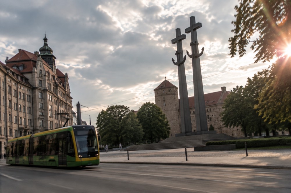 A modern tram moving along a street in central Poznan past stone buildings