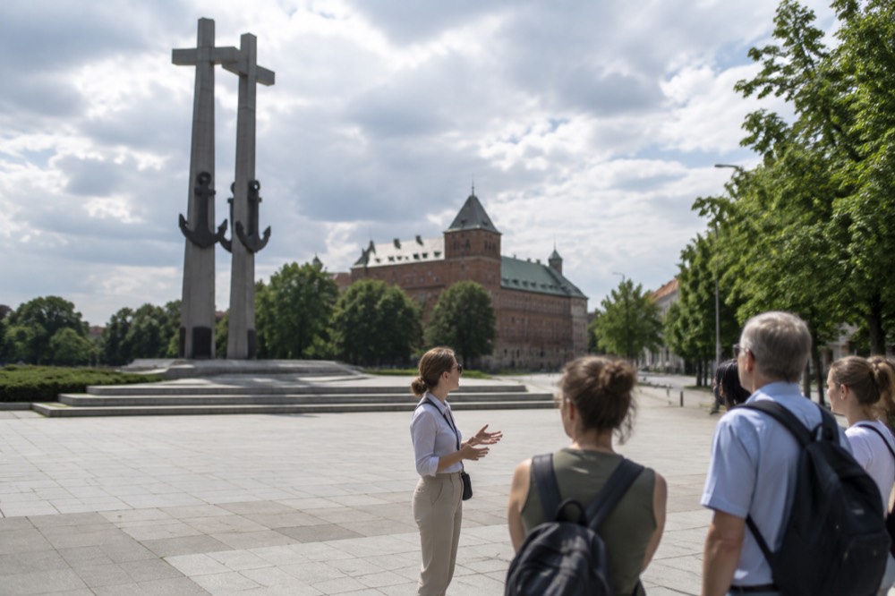A guide speaking to a small group of visitors on a city street in Poznan