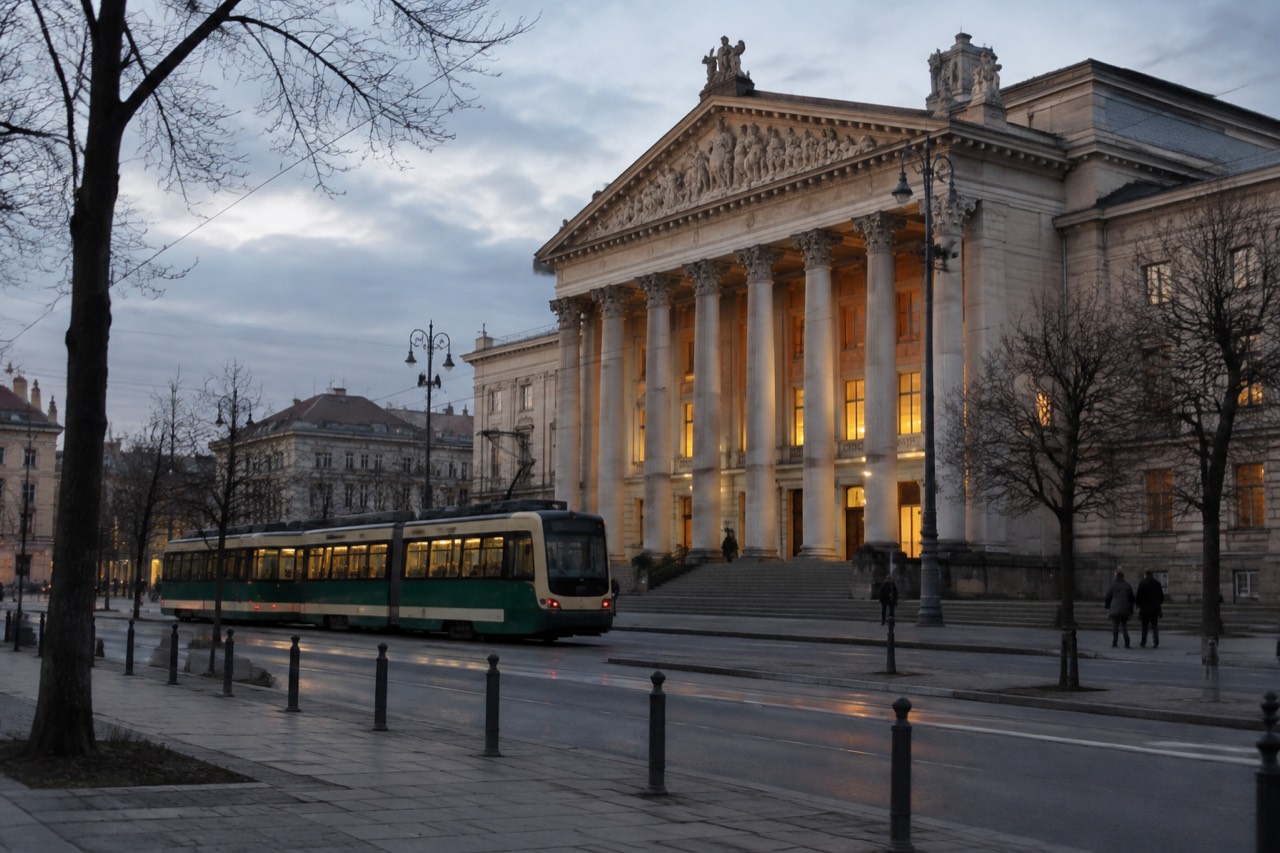 The evening facade of an opera house in central Poznan with warm light glowing from tall windows