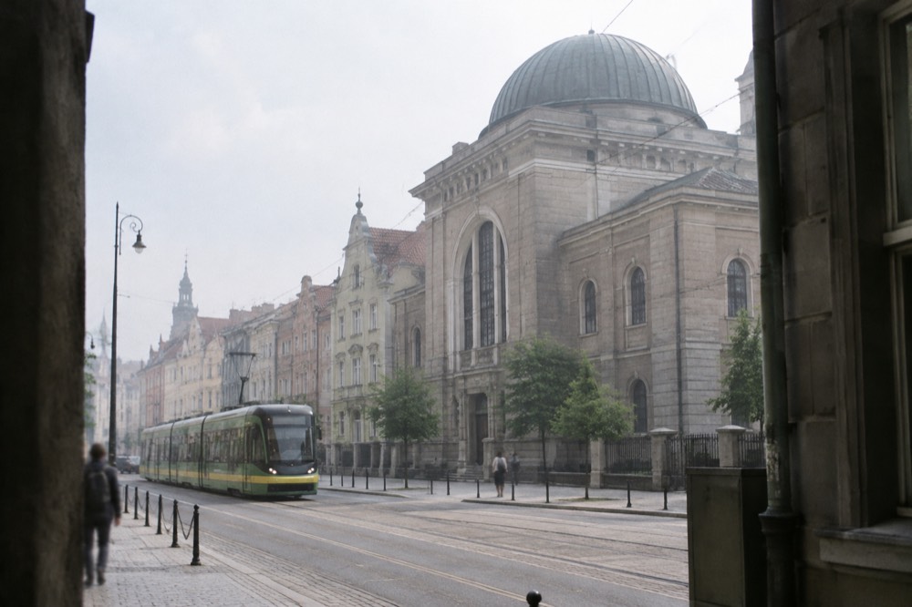A modern tram moving along a street with historic buildings in central Poznan