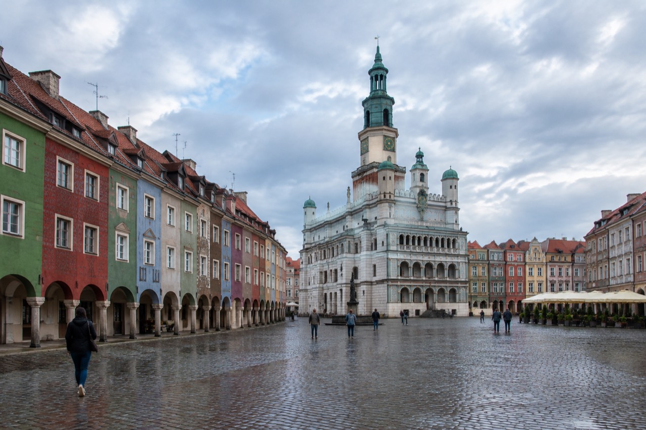 Renaissance town hall with a clock tower rising above colorful merchant houses on a large old market square