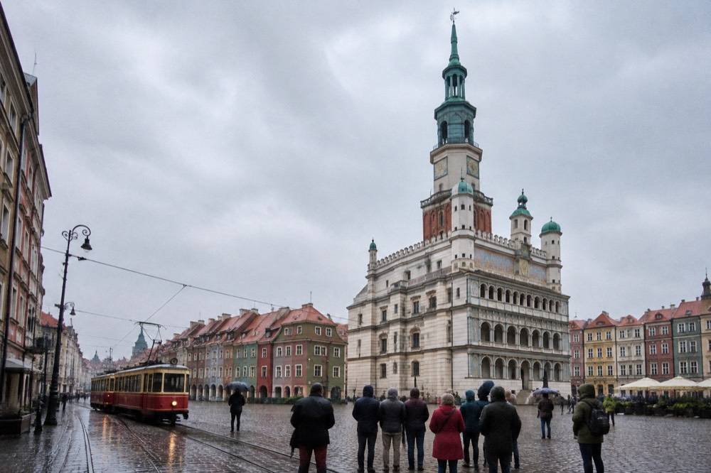 Vintage tram passing historic buildings on a city street in Poznan