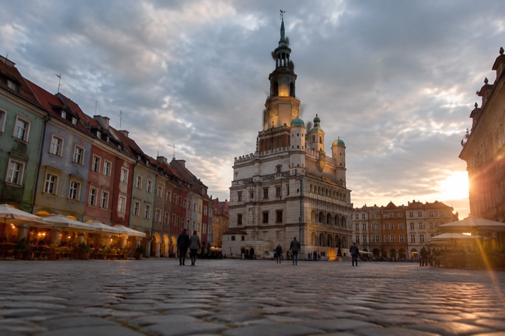 Old market square at dusk with illuminated town hall tower and warm cafe lights