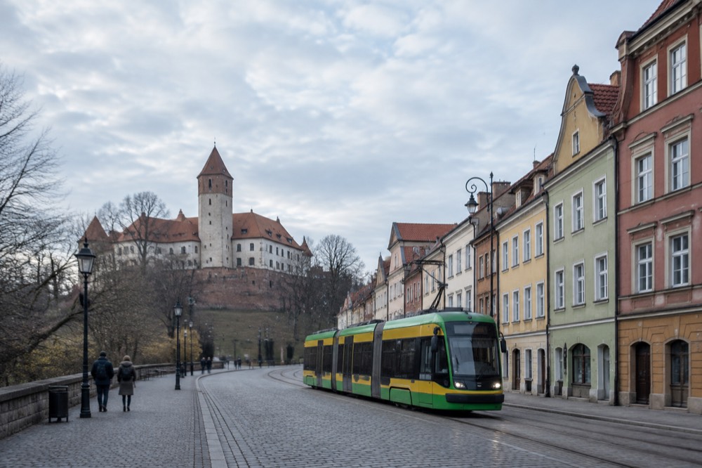 A tram passing colourful old town buildings near a cobbled street