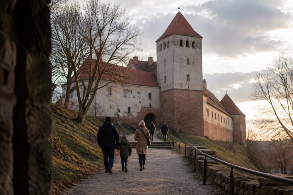 A family walking up a path toward a castle entrance on a hill