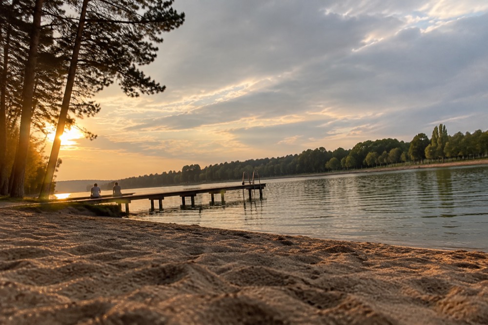 A wide artificial lake with a promenade and trees on the far shore