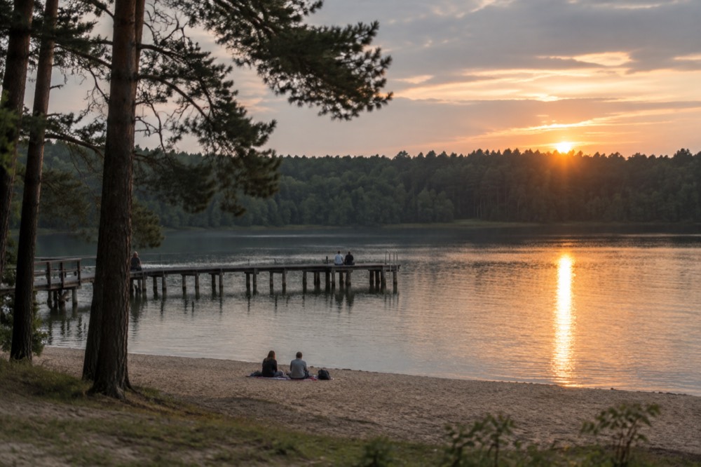 Sunset light over a calm lake with a forest silhouette in Poznan