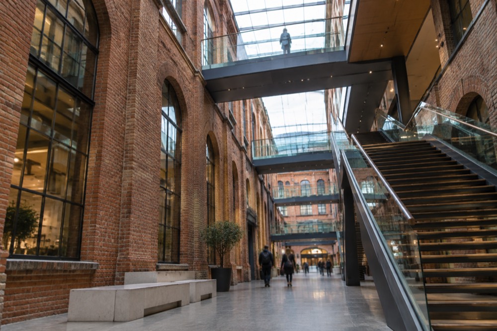 Interior walkway inside Stary Browar with exposed brick brewery walls and modern staircases
