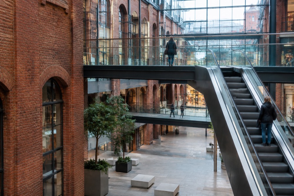 An escalator and walkway crossing a light-filled atrium inside Stary Browar