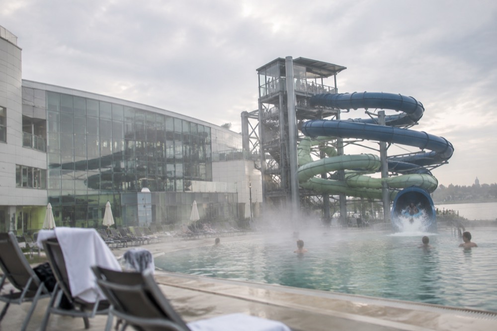 Water slide tower with riders descending into a splash pool